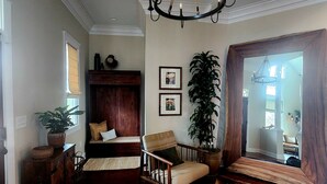 Un salon spacieux agrémenté d’un grand lustre, d’un banc en bois, d’un canapé et d’une grande fenêtre avec des rideaux.