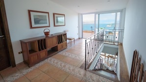 A spacious living area with a wooden cabinet, two framed pictures on the wall, and a balcony with a view of the sea. - Villa Savoia in Sorrento (Sorrento)