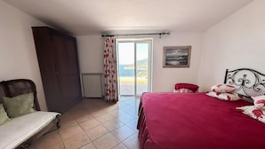 A bedroom with a bed, a chair, a radiator, a window with curtains, and a painting on the wall. - Villa Savoia in Sorrento (Sorrento)