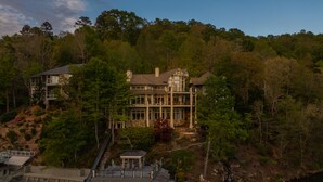 A large, multi-story house with a dock and a waterfall in the background. - Parabull's Point, Lake Lure, Luxury House with water slide (Lake Lure)