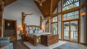 A rustic bedroom with a wooden headboard, a large window, and a view of the outside. - Parabull's Point, Lake Lure, Luxury House with water slide (Lake Lure)