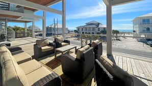 Un espace extérieur aménagé, abrité et doté de mobilier en osier, offrant une vue sur la plage et l’océan.