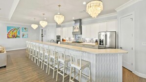 Une cuisine moderne dotée d’un îlot central, de meubles blancs et d’un réfrigérateur en acier inoxydable.
