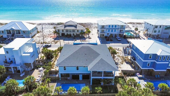 Un quartier résidentiel situé sur la côte, comprenant plusieurs maisons, une plage et une piscine.