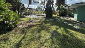 A well-maintained garden with a pool, palm trees, and a gazebo.