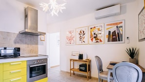 A modern kitchen with a microwave, oven, and a wooden table with chairs. - Illyria Old Town Apartment by DuHomes (Dubrovnik)
