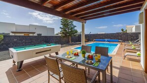 A pool area with a pool table, lounge chairs, and a dining table set for two. - Villa Argentina - Three Bedroom Villa, Sleeps 6 (Montaña Roja)