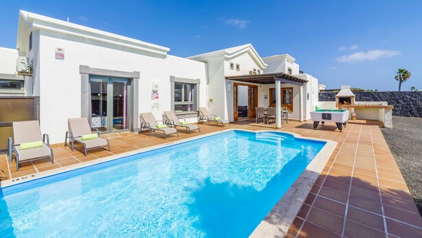 A modern villa with a swimming pool, outdoor seating, and a stone wall backdrop. - Villa Argentina - Three Bedroom Villa, Sleeps 6 (Montaña Roja)