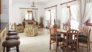 A dining area with a round wooden table and chairs, a sofa, and a bar area with stools.