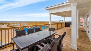 Una terraza techada al aire libre con una mesa y sillas de comedor, con vista a la playa.