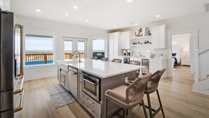 Una cocina moderna con una isla grande, electrodomésticos de acero inoxidable y vistas al océano.