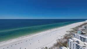 Une plage avec une longue étendue de sable et un ensemble de bâtiments comprenant plusieurs étages et des balcons.