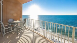 Een balkon met uitzicht op zee, een tafel en stoelen.