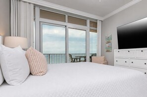 Et hotelværelse med en stor seng, et fjernsyn, en balkon med udsigt og et kommode.