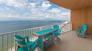 A balcony with a table and chairs, a view of the ocean, and a railing.