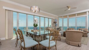A spacious dining area with a glass table and chairs, a chandelier, and a view of the ocean. - Phoenix Gulf Tower 2604 Seaside Escape (Orange Beach)