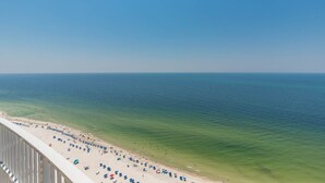 A beach with umbrellas and people, a clear sky, and the ocean. - Phoenix Gulf Tower 2604 Seaside Escape (Orange Beach)