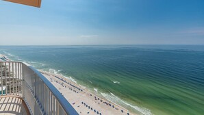 A beach with a railing, a clear view of the ocean, and a sandy shore.