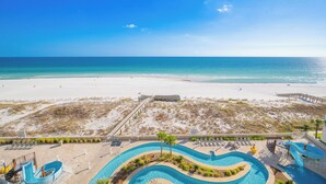 Un complejo turístico en la playa con zona de piscina, playa de arena y vistas claras al océano.