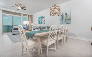 Un coin repas avec une table et des chaises, un ventilateur de plafond et un tableau accroché au mur.