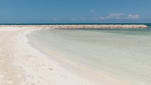 Une plage avec une eau claire et peu profonde et un rivage sablonneux.