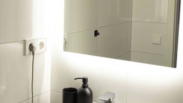 A bathroom with a white sink, a mirror, and a black soap dispenser.
