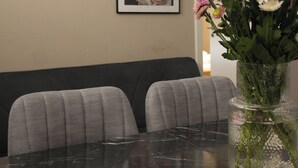 A dining area with a marble table, a vase of flowers, framed artwork on the wall, and a white device on the table. - Kuzey Apartments (Kappel-Grafenhausen)