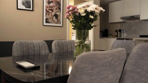 A dining area with a marble table, grey upholstered chairs, a vase with flowers, and framed artwork on the wall. - Kuzey Apartments (Kappel-Grafenhausen)