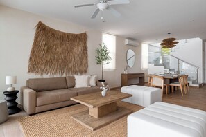 A modern living room with a sofa, coffee table, and dining area. - Large 3BR family House with Pool (Cancún)
