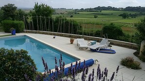 Una piscina con sillones de descanso y vistas al campo.