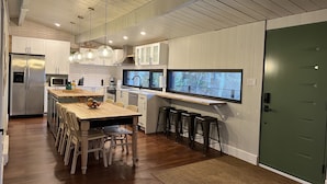 A modern kitchen with a central island, bar stools, and a large window. - New construction, This Chalet is ready to enjoy all seasons ! (Saint-Michel-Des-Saints)