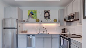A modern kitchen with white cabinetry, stainless steel appliances, and decorative wall art.