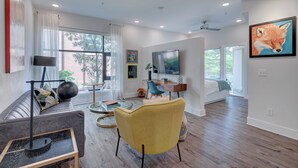 A modern living room with a sofa, a yellow armchair, a coffee table, and a TV.