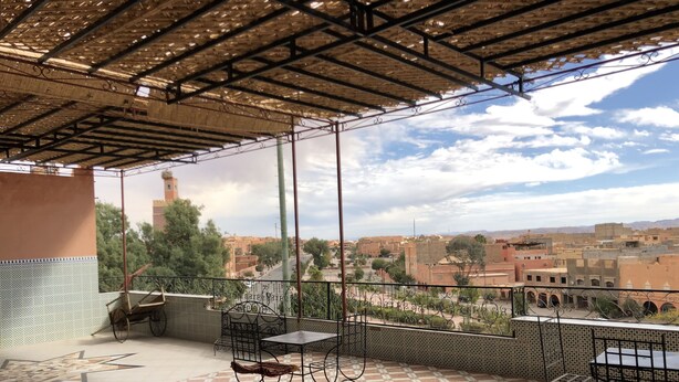 A terrace with a patterned floor, metal furniture, and a view of a cityscape. - Aigle Appart Hôtel  (Ouarzazate)
