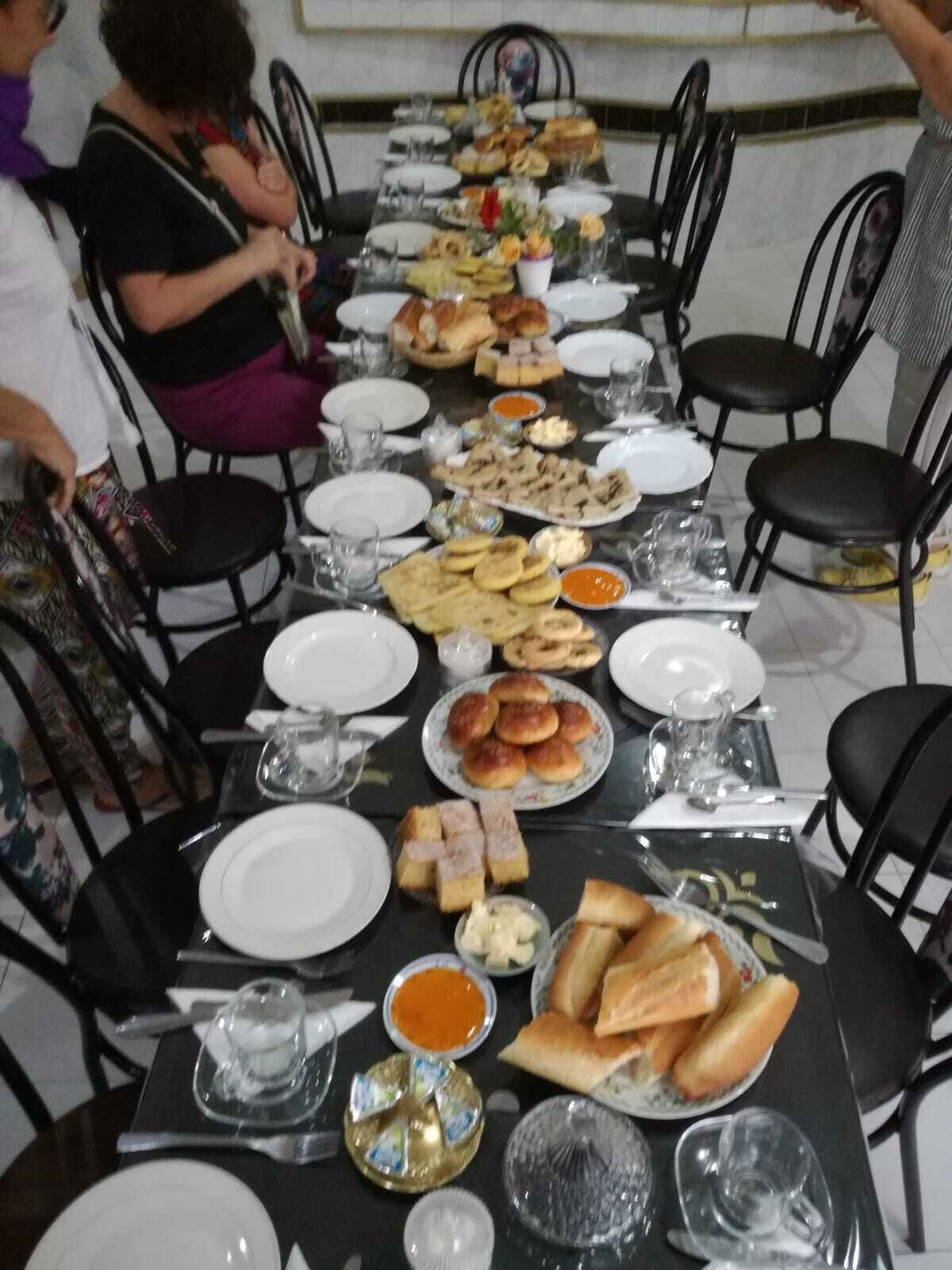 A long dining table set with various dishes, plates, and glasses, surrounded by black chairs.