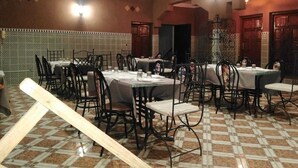 A restaurant with multiple tables and chairs, a tiled floor, and a high ceiling with exposed beams. - Aigle Appart Hôtel  (Ouarzazate)