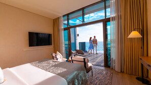 Habitación de hotel con cama, televisión, escritorio y vista al mar.