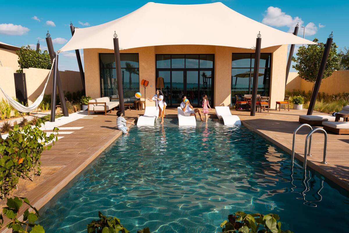 Un espace piscine doté de chaises longues, d’un coin salon abrité et offrant une vue dégagée sur la piscine.
