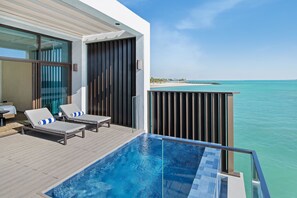 Un balcón moderno con piscina, sillones de descanso y vistas al océano.