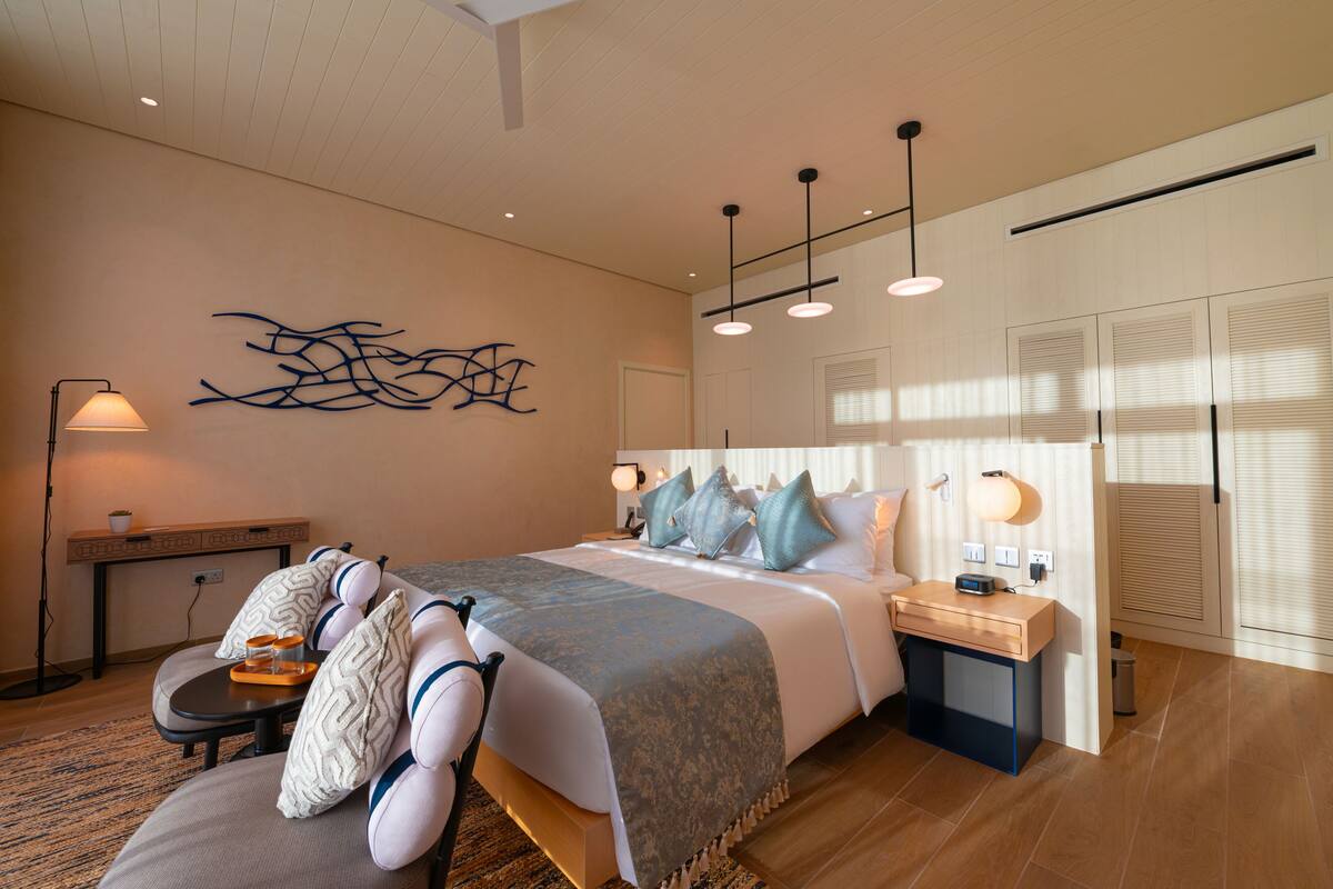 Une chambre moderne avec un grand lit, des tables de chevet, un bureau et une œuvre d’art accrochée au mur.
