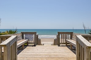 A wooden boardwalk leading to a beach with a sign indicating private property and no trespassing.