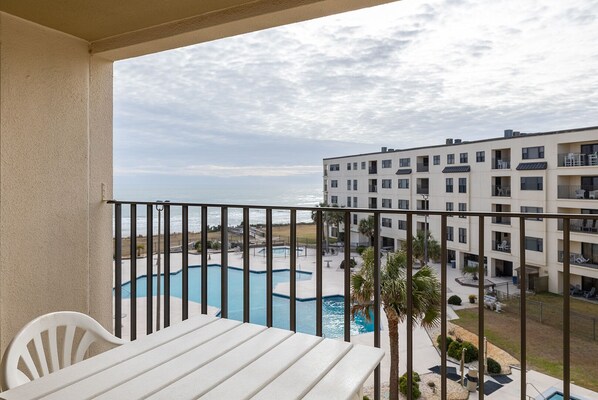 A balcony with a view of a swimming pool and a building with multiple balconies.