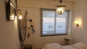 A bedroom with a bed, a window with a view, a wall-mounted light, and a small bedside table. - Appartement à LA Ciotat Avec Grande Terrasse de 50m² à Deux pas du Vieux Port (LA CIOTAT)