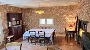 Un coin repas avec un mur en pierre, une table avec des chaises, un buffet en bois et un luminaire suspendu.