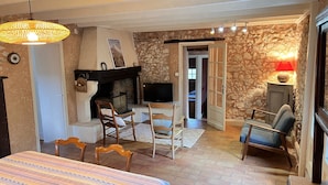 Une pièce chaleureuse avec une cheminée, un téléviseur et un coin repas comprenant des chaises et une table.