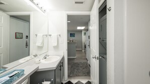 Ein modernes Badezimmer mit zwei Waschbecken, einem großen Spiegel und einem begehbaren Kleiderschrank.