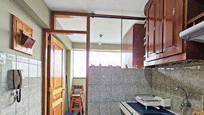 Una cucina con lavello, pensili e una scopa nell'angolo.