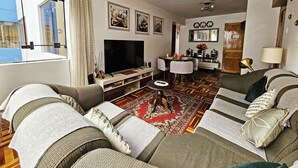 Un soggiorno con divano, TV a schermo piatto, tavolino da caffè e tappeto decorato.
