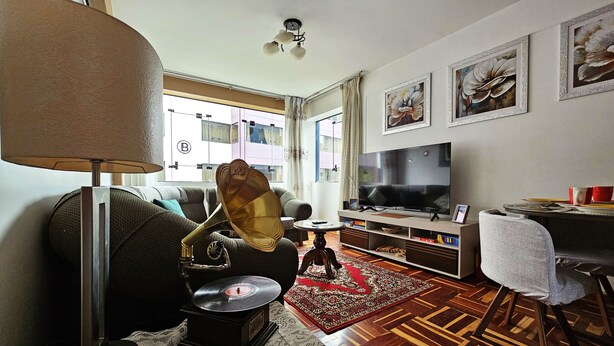 Un soggiorno con divano, lampada, giradischi, televisore e zona pranzo con tavolo e sedie.