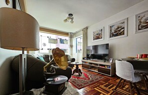 A living room with a sofa, a lamp, a record player, a TV, and a dining area with a table and chairs. - Pama Wasi - Casa del Puma (Cusco)